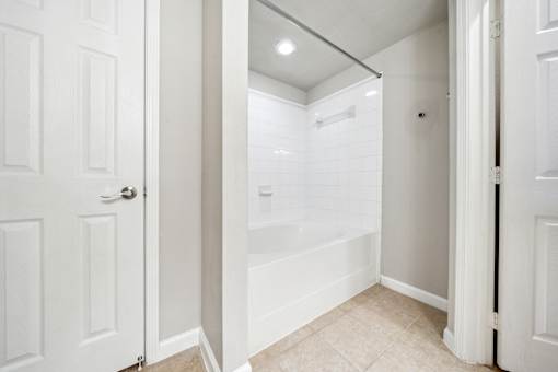 A white bathroom with a walk-in shower and a toilet at The Atlantic Stone Oak Apartments, San Antonio