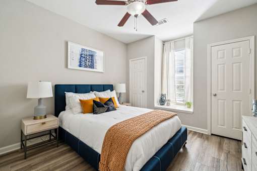 A bedroom with a bed, nightstand, and a ceiling fan at The Atlantic Stone Oak Apartments, San Antonio