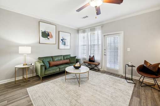 A living room with a green couch, a coffee table, and a ceiling fan at The Atlantic Stone Oak Apartments, San Antonio