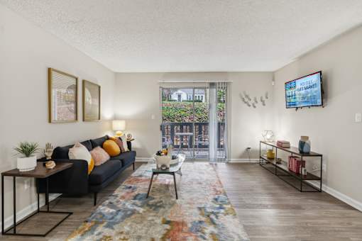 A living room with a black couch, a rug, and a TV mounted on the wall at The Atlantic Loring Heights, Atlanta, Georgia