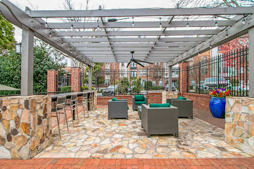 A patio with a stone wall and a metal pergola at The Atlantic Buckhead Apartments, Atlanta