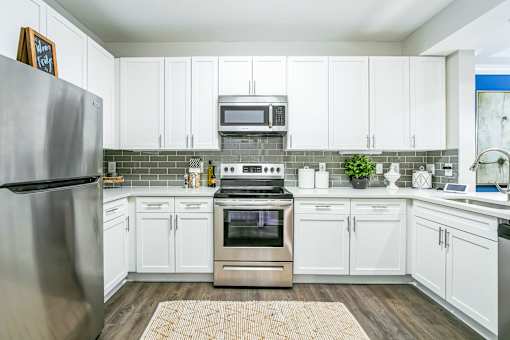A kitchen with white cabinets and a stainless steel refrigerator at The Atlantic Buckhead Apartments, Atlanta, GA, 30305