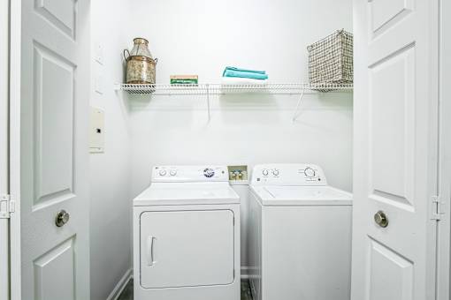 A white laundry room with a washer and dryer at The Atlantic Buckhead Apartments, Atlanta, GA