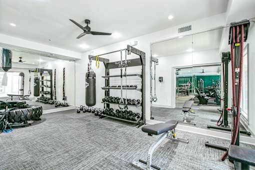 A spacious gym with a variety of equipment including a punching bag, weight racks, and a bench at The Atlantic Buckhead Apartments, Atlanta, GA, 30305
