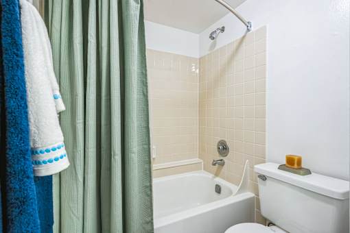 A white toilet sits next to a bathtub in a bathroom at Boca Colony Apartments, Florida, 33433