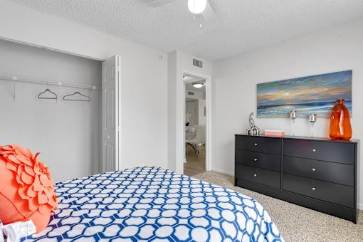 A bedroom with a blue and white patterned bedspread at Boca Colony Apartments, Florida