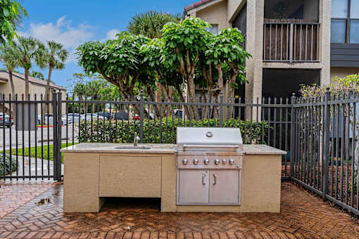 A small outdoor kitchen with a grill and sink at Boca Colony Apartments, Boca Raton, Florida