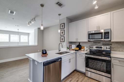 A modern kitchen with white cabinets and stainless steel appliances.