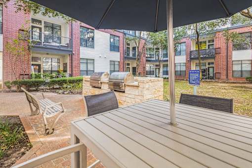 A patio with a table and chairs under an umbrella.