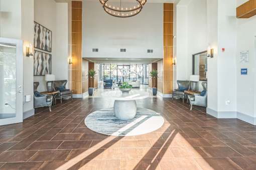 A large, well-lit lobby with a circular rug and a chandelier  at The Atlantic Memorial, Houston
