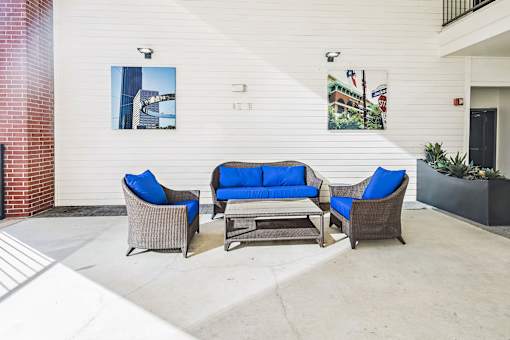 A patio with a couch, two chairs and a table.
