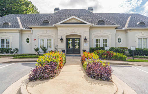A white building with a black door and windows surrounded by flowers.at The Atlantic Canton Ridge, Canton  