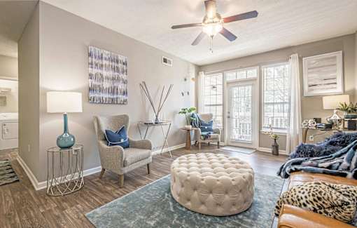 A living room with a leopard print couch and a round ottoman.at The Atlantic Canton Ridge, Canton, 30114  