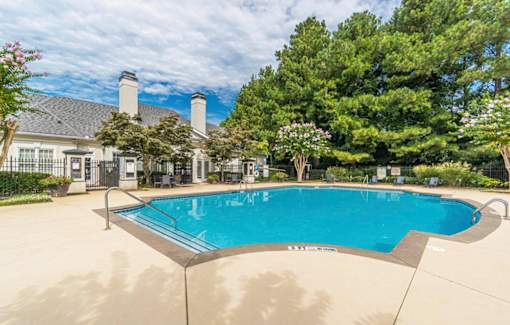 A large outdoor swimming pool surrounded by a fence and trees.at The Atlantic Canton Ridge, Georgia  