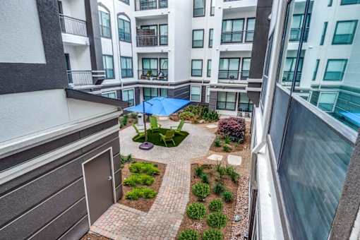 A courtyard with a blue umbrella and a small garden. at Montecito Apartments, Houston, Texas