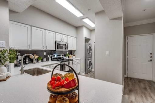 A kitchen with a white countertop and a basket of bagels and tomatoes on it. at Montecito Apartments, Houston, TX, 77056