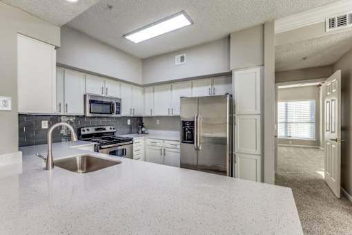 A kitchen with a stainless steel refrigerator, microwave, and sink. at Montecito Apartments, Houston, TX