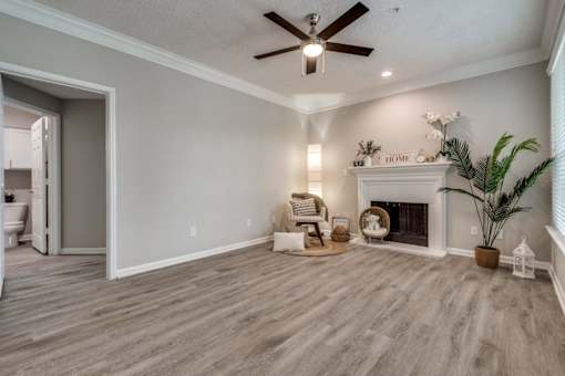 A living room with a fireplace and a ceiling fan. at Montecito Apartments, Texas, 77056