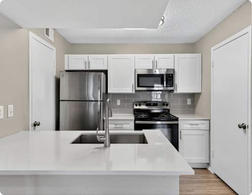 A kitchen with white cabinets and appliances at Logans Mill, Austin, TX.