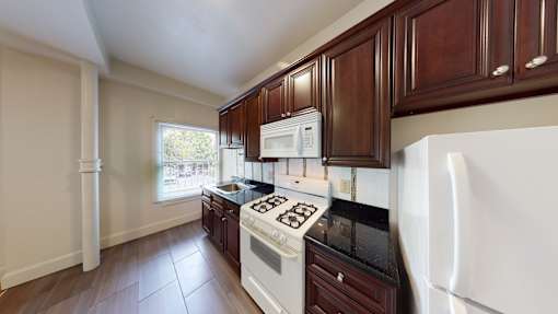 A kitchen with white appliances and dark wood cabinets.