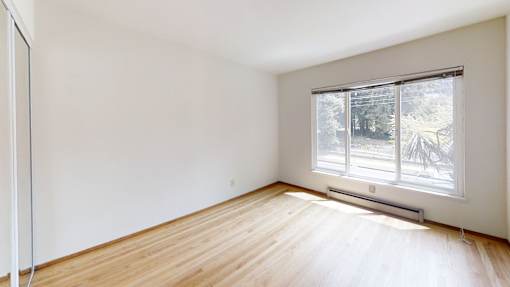 Empty room with a window and wooden floor.