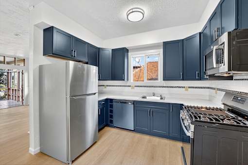 A kitchen with a stainless steel refrigerator and dark blue cabinets.