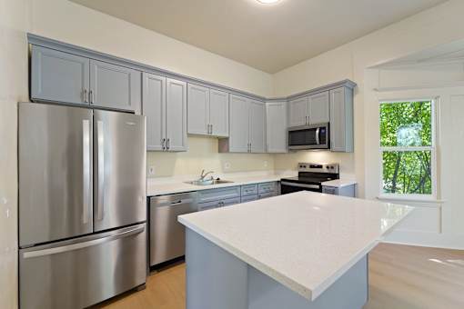 A kitchen with a refrigerator, microwave, and oven.