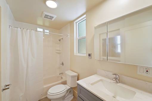A white bathroom with a toilet, sink, and shower.
