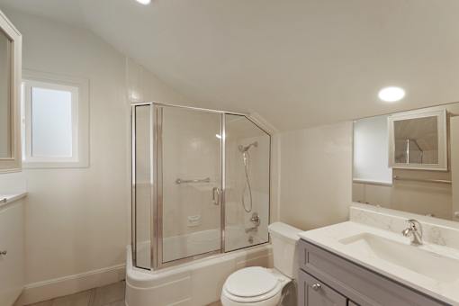 A white bathroom with a toilet, sink, and shower.