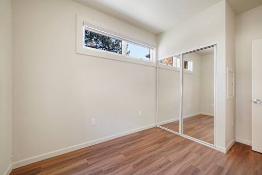 A room with a sliding glass door and wood flooring.