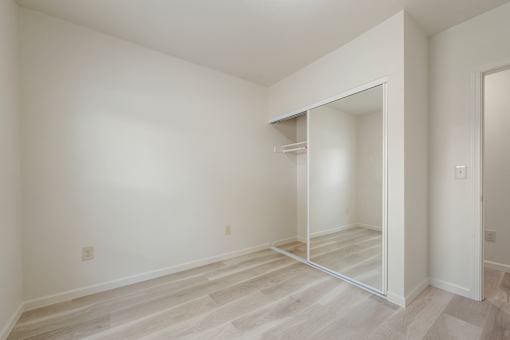 A white room with a wardrobe and a mirror.