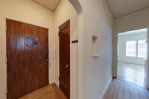 A hallway with a brown door on the left and a white door on the right.