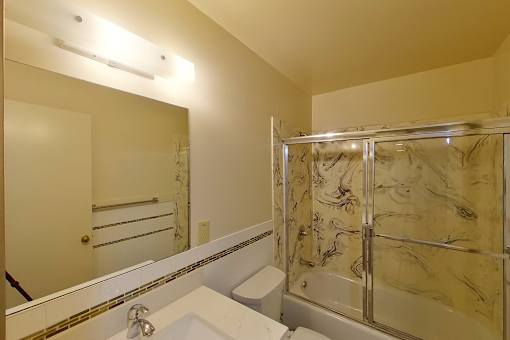 A bathroom with a marble shower and a white sink.