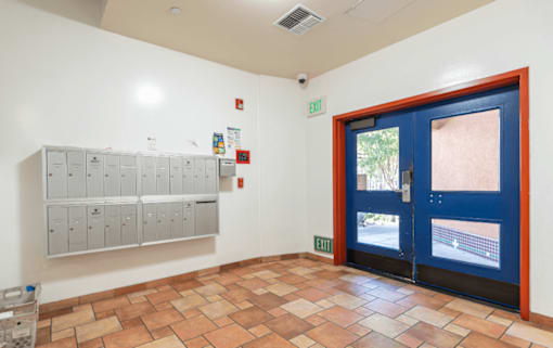 A hallway with a blue door and a wall of lockers.