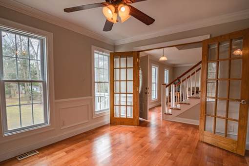 a empty living room with a wood floor and a ceiling fan