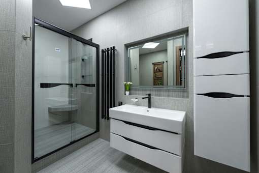 A modern bathroom with a white sink and a glass shower.