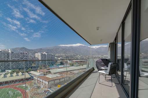 A balcony with a chair and a view of a city and mountains.