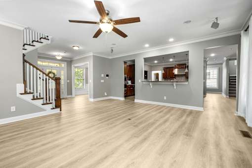 A spacious living room with a ceiling fan and hardwood floors.