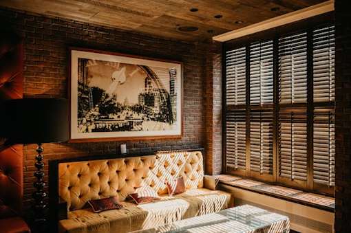 A room with a tufted sofa and a framed picture on the wall.