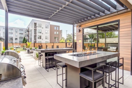 an outdoor patio with tables and chairs and a grill