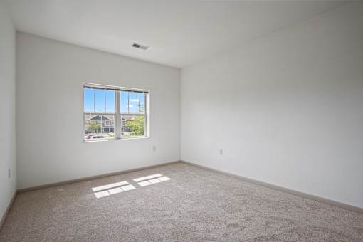 A room with a large window and a carpeted floor.