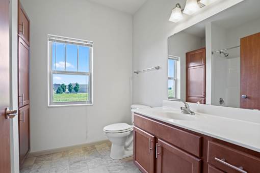 A bathroom with a toilet, sink, and a window.