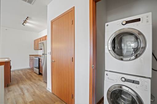 A washing machine is on top of a dryer in a small apartment.