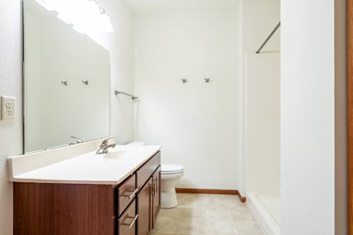 A bathroom with a sink, mirror, toilet and a shower.
