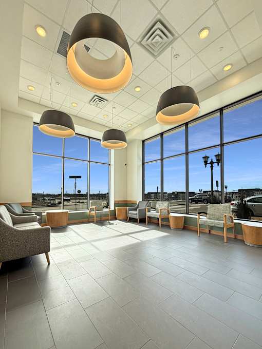 A spacious waiting area with grey tiled floors and large windows.