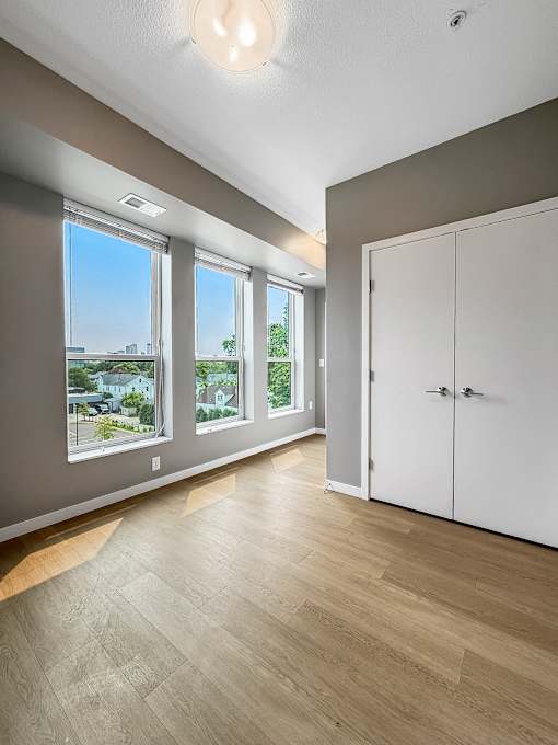 A room with a white door and a window overlooking a cityscape.