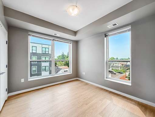 A room with a large window showing a view of a street and houses.