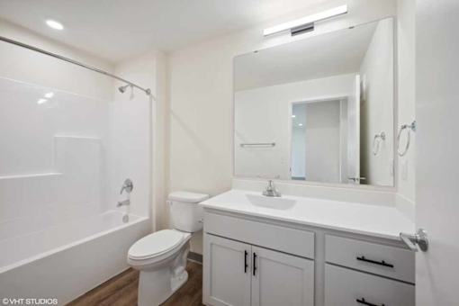 A white bathroom with a toilet, sink, and mirror.