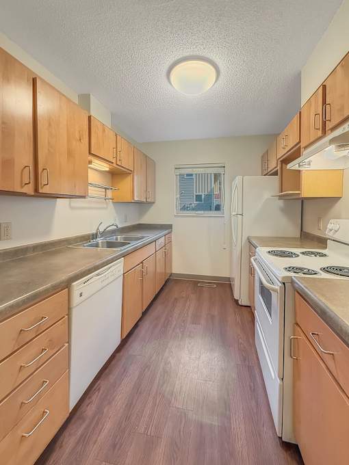 A kitchen with white appliances and wooden cabinets.