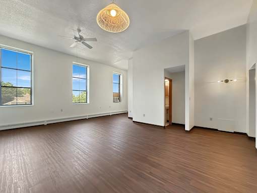 A room with a ceiling fan and wooden flooring.